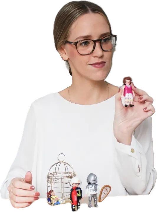Sofía Gimbert sosteniendo una figura de Playmobil, con otras figuras sobre la mesa